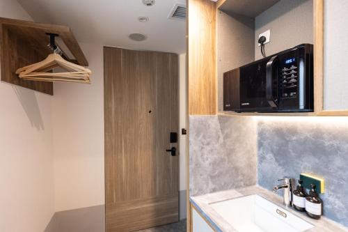 a kitchen with a microwave and a sink at Heritage Collection on Victoria - Mobile App Check-In in Singapore