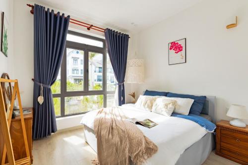 a bedroom with a bed with blue curtains and a window at Boho Boutique Da Lat - View nhà lồng lãng mạn in Da Thanh