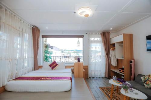 a bedroom with two beds and a large window at Sweet Lavender Hotel in Da Lat
