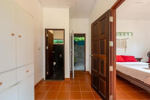a bedroom with a bed and a door leading to a bathroom at Sun & Sand Bungalows in Thongsala