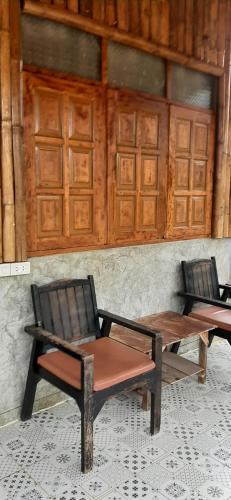 2 sillas, mesa de madera y banco en สวัสดีเมืองคองคาเฟ่, en Ban Wang Masiu