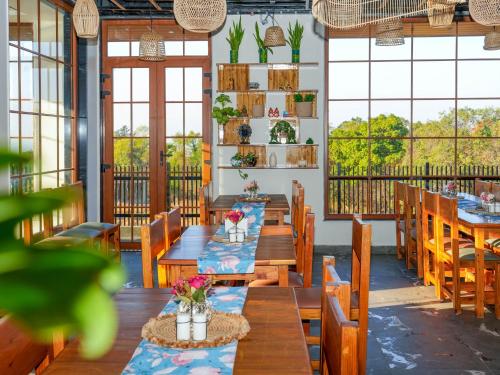 a restaurant with wooden tables and chairs and windows at Hotel Hill Sides Inn in Pathyar