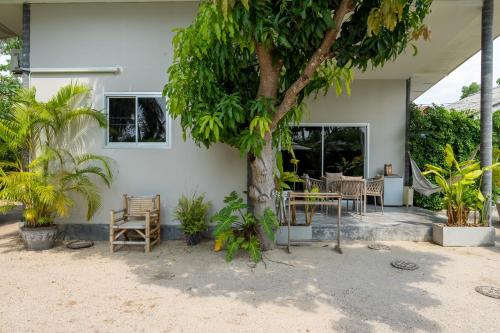 a house with a tree and a table and chairs at Sun & Sand Bungalows in Thongsala