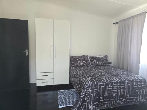 a bedroom with a bed and a white cabinet at Majhiya on Ferndale apt in Gqeberha