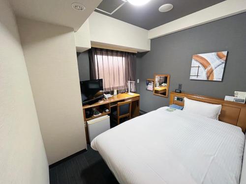 a bedroom with a bed and a desk with a computer at Hotel Route-Inn Naha Asahibashi Eki Higashi in Naha