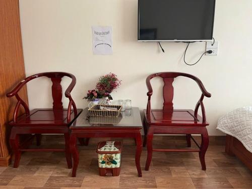 two chairs and a table with a tv on a wall at Công Thành Hotel in Lao Cai