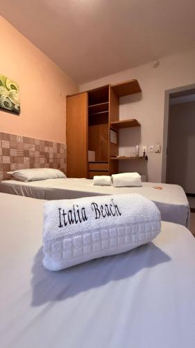 a hotel room with two beds with a towel on the bed at Hotel Italia Beach - Na Beira Mar Natal RN in Natal