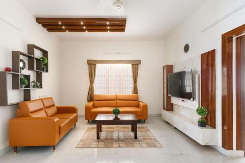 a living room with two chairs and a tv at Mistyblue Suites in Bengaluru