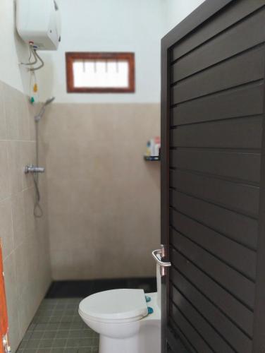 a bathroom with a toilet and a door at Uthe House in Pacet