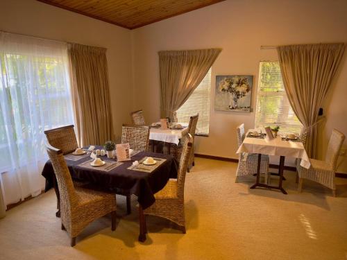 a dining room with tables and chairs and windows at Kliprand Guest House in Springbok