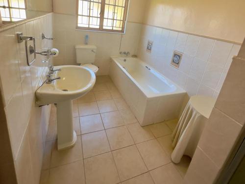 a bathroom with a sink and a tub and a toilet at Kliprand Guest House in Springbok