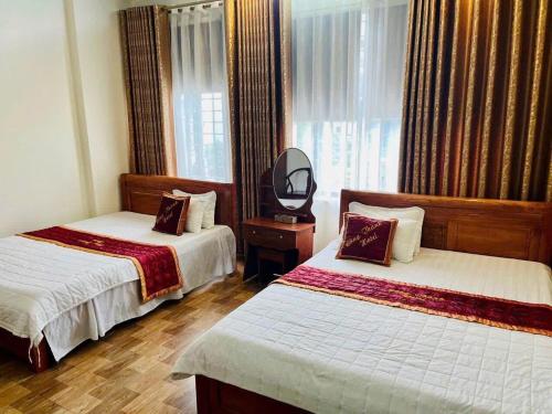 a hotel room with two beds and a mirror at Công Thành Hotel in Lao Cai