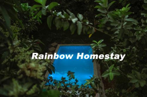 a sign for rainbow homesay is seen through trees at Rainbow Homestay 2BHK with swimming Pool at Auroville in Auroville