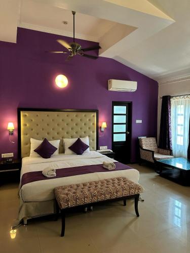 a bedroom with a large bed with purple walls at Silver Sands Hideaway Resort, Candolim in Candolim