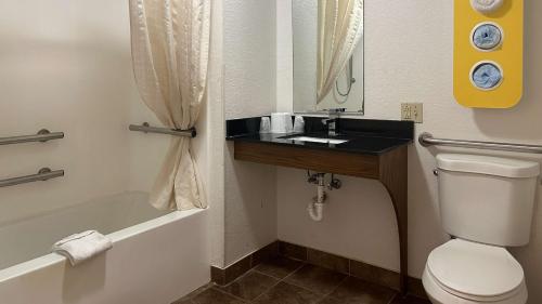 a bathroom with a toilet and a sink and a tub at Motel 6-Waterloo, IA in Waterloo