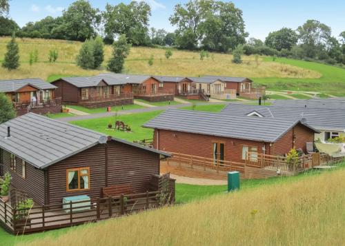 a group of wooden cabins in a field at Badgers Retreat Holiday Park in Hunton
