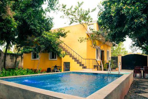 a swimming pool in front of a yellow house at Rainbow Homestay 2BHK with swimming Pool at Auroville in Auroville