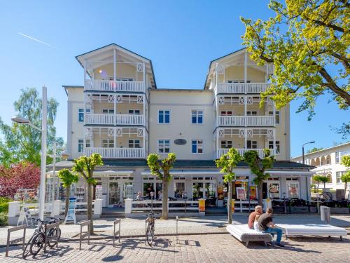ein großes Gebäude mit Leuten, die auf Bänken davor sitzen in der Unterkunft Villa Seerose - Appartement 11 in Ostseebad Sellin