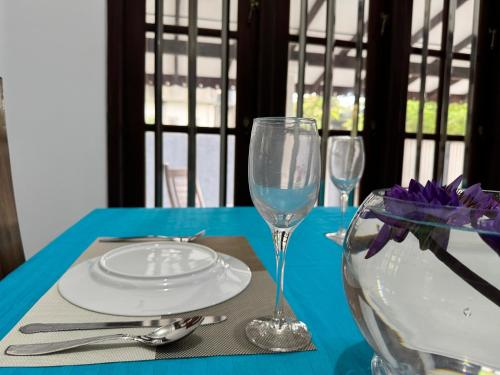 a blue table with a plate and two wine glasses at Seahorse Villa in Galle