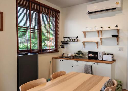 a kitchen with a wooden table and a refrigerator at The Hilltop Erawan in Si Sawat