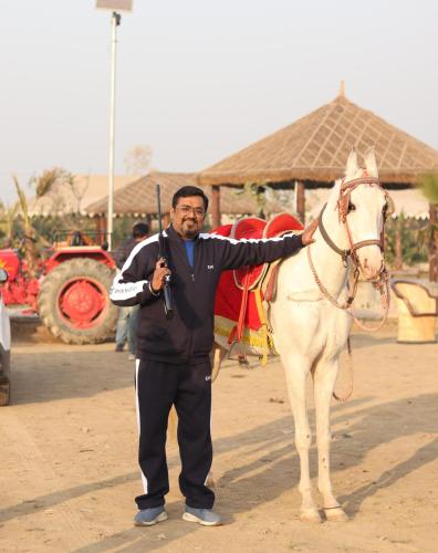 a man standing next to a white horse at MST Farm And Resort in Ghaziabad