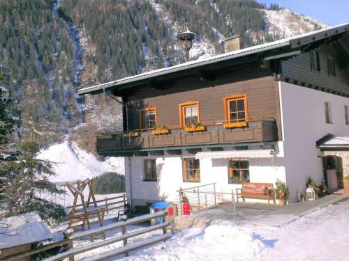 Una casa con balcón y una montaña cubierta de nieve. en Kleintierhof Seidl-Eder, en Rauris