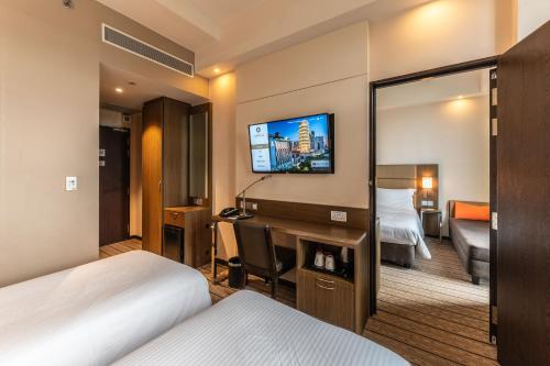 a hotel room with a bedroom with a desk and a tv at Hotel Traveltine in Singapore