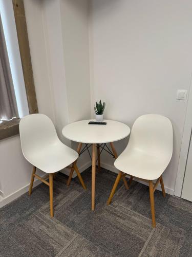 two white chairs and a table in a room at Vernieuwde kamers in het centrum van Brugge in Bruges
