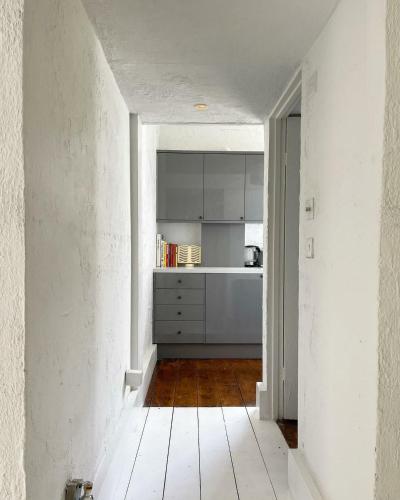 a kitchen with white cabinets and a wooden floor at One Bed Garden Flat - Prime location - Free Onsite Parking - Own Entrance in Brighton & Hove