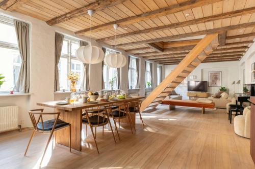 a living room with a wooden table and a staircase at Charming 4BR Duplex in Nørrebro in Copenhagen