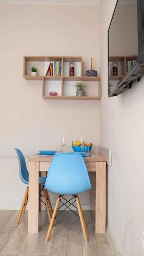 a dining room table with a blue chair and a mirror at Студио Булаир 1 с безплатен паркинг in Burgas