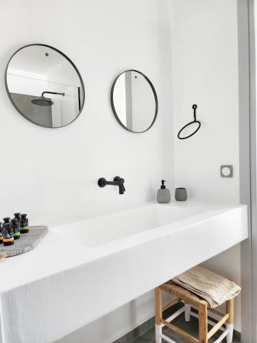 a bathroom with a white sink and two mirrors at Hidden Hill Naxos Villas in Kastraki