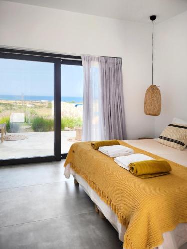 a bedroom with a bed and a large window at Hidden Hill Naxos Villas in Kastraki