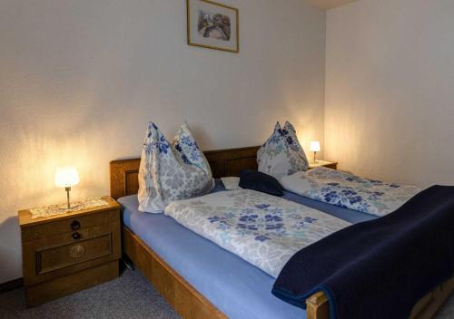 a bedroom with two beds and a night stand with lamps at Haus Hahnenkamm in Nesselwängle