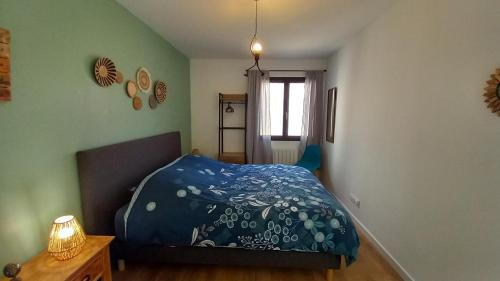 ein Schlafzimmer mit einem Bett mit einer blauen Bettdecke in der Unterkunft Appartement avec terrasse dans maison individuelle in Ceyreste
