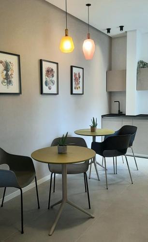 two tables and chairs in a room with a kitchen at Vittoria Rooms in Siracusa