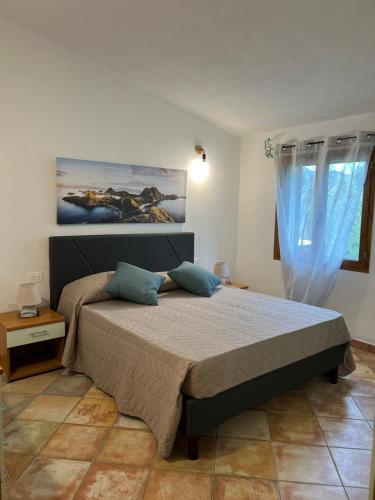 a bedroom with a large bed with blue pillows at Villa Scirocco in Cala Liberotto