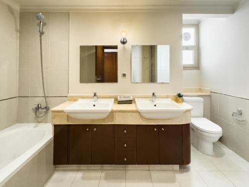 ein Badezimmer mit zwei Waschbecken und einer Badewanne und einer Toilette in der Unterkunft Sunny Cairo City Center l Serviced l Golf l Pool l Gym l 2 in Kairo