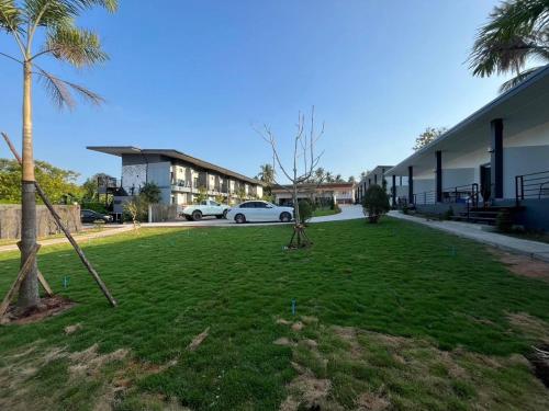 a grassy yard with a car parked in front of a building at Hillside Premium Hotel in Ban Huai Chiat