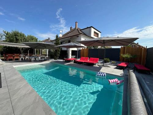 - une piscine avec des chaises rouges et des parasols dans l'établissement Syreland gîte meublé, à Duttlenheim