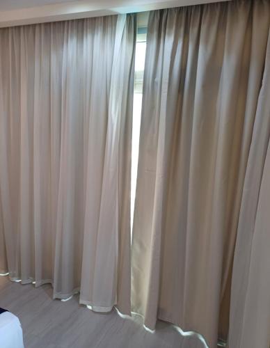 a bedroom with white curtains and a window at Hurghada Mirage Bay Hotel & Aquapark in Hurghada