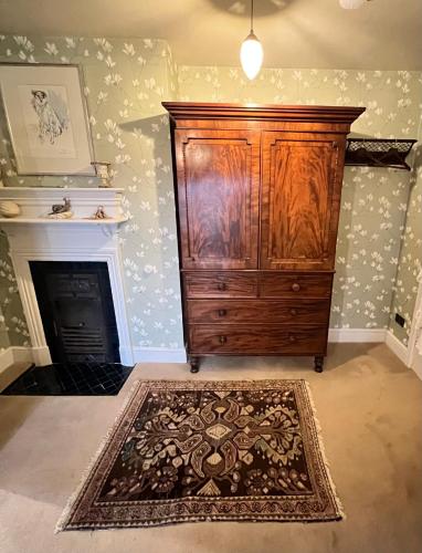 a room with a large wooden cabinet and a fireplace at Uplands Guest House in Ledbury