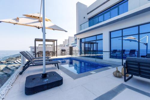 a house with a swimming pool and a building at Overlooking Pool, Mountain and Sea 6BR Villa with Two Assistant Room, Heated Pool, BBQ Area, Al Dana Island, Fujairah by Deluxe Holiday Homes in Fujairah