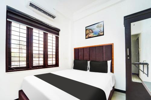 a bedroom with a large bed and two windows at Super Hotel O Attukal Near Attakulangara formerly Remya Residency in Trivandrum