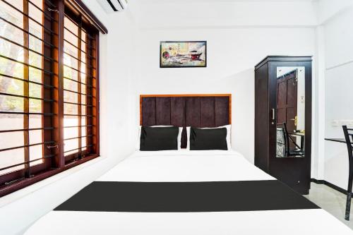 a bedroom with a bed and a large window at Super Hotel O Attukal Near Attakulangara formerly Remya Residency in Trivandrum