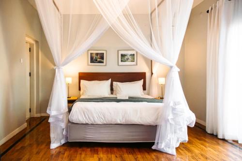 a bedroom with a canopy bed with white drapes at Joli Guesthouse in Maputo