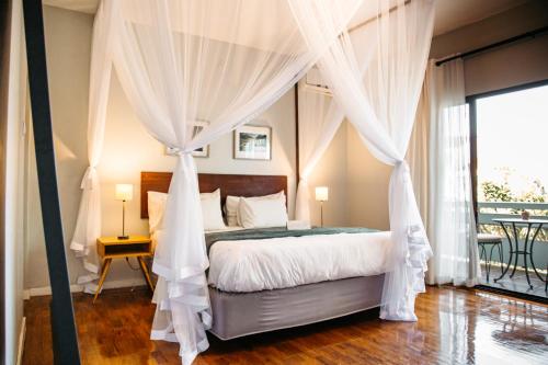 a bedroom with a canopy bed with white curtains at Joli Guesthouse in Maputo