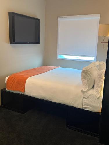 a bedroom with a bed with a tv on the wall at Hotel Sky Sandton in Johannesburg