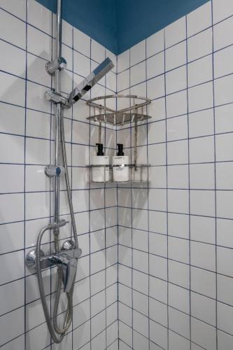 a shower in a bathroom with white tiled walls at Mandera's Boutique Suites & Dorms in Valletta