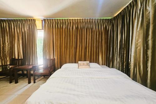 Un dormitorio con una cama y una ventana con cortinas. en Thai Gallery Baantawai, en Chiang Mai